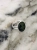 Silver ring with an oval green nephrite stone photographed on a light marble surface.