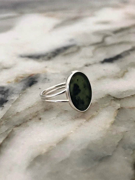 Close-up of an oval nephrite stone measuring 14 × 10 mm set in a delicate sterling silver band.