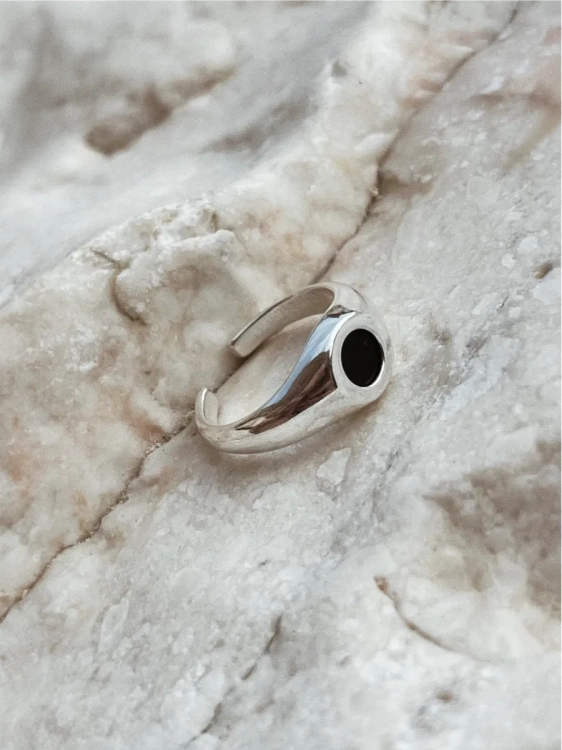 Silver signet ring with chocolate flint gemstone on light stone background.