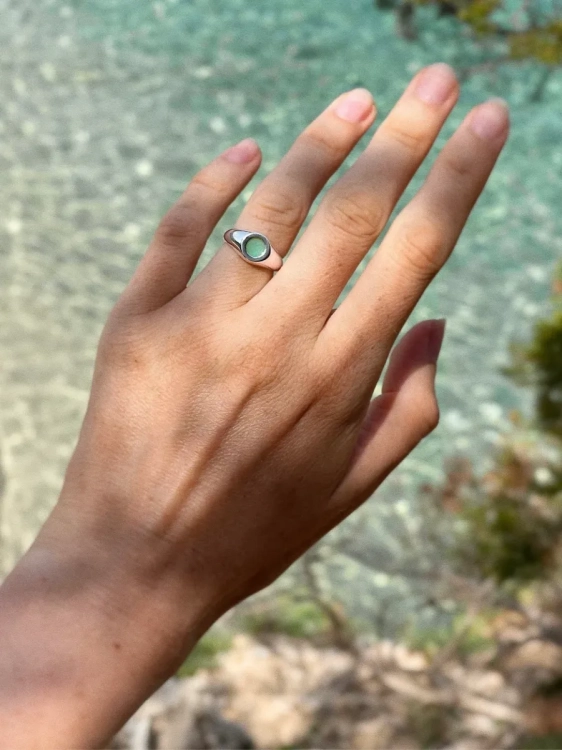 Silver signet ring with chrysoprase in turquoise shade on a woman’s hand.