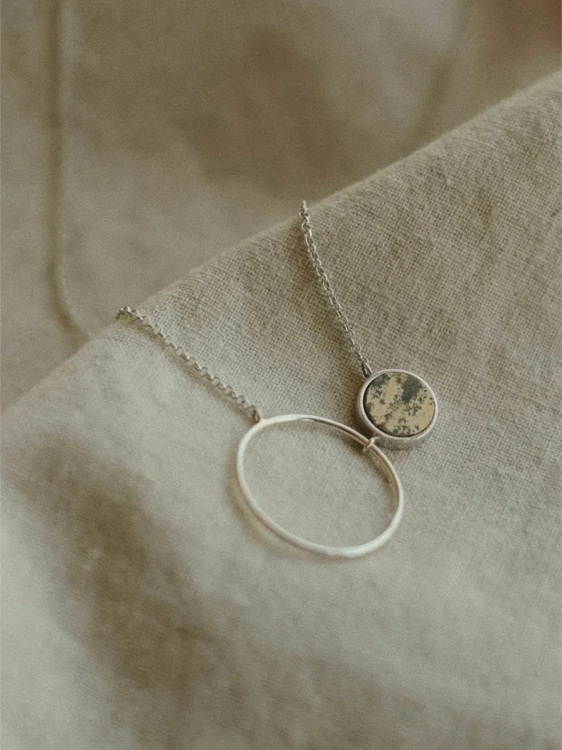 Close-up of silver necklace with dendrite gemstone and circle pendant – jewellery with Polish stones by Kamena.