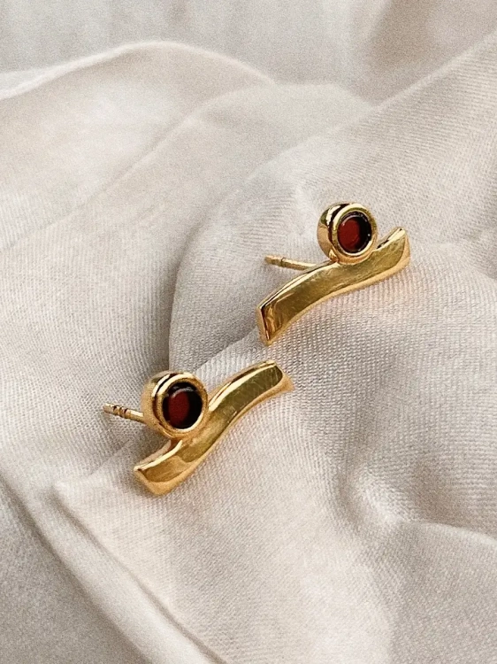 Sculptural gold-plated earrings with cognac Baltic amber, close-up detail