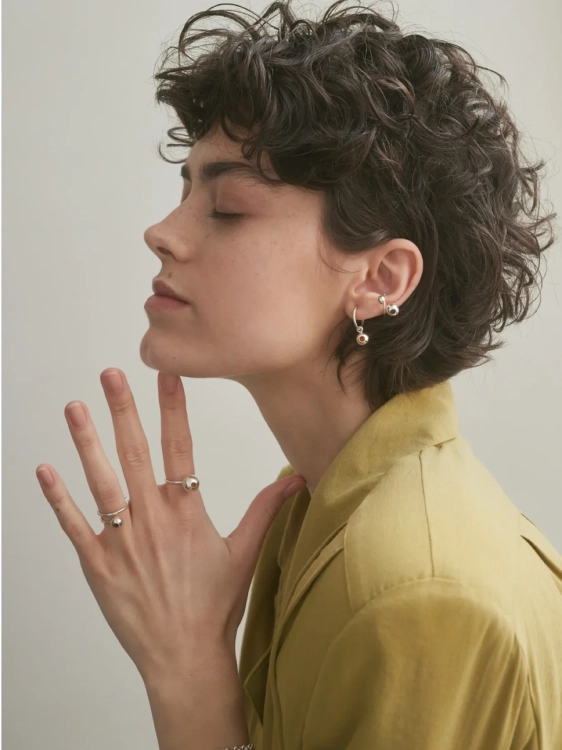 Modern sterling silver hoop earrings with amber detail worn by model
