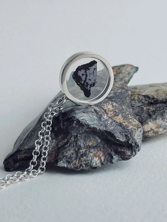 Close-up of a sterling silver pendant with iron meteorite fragments set in resin