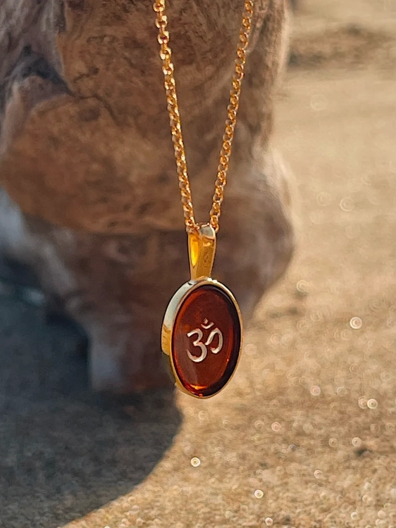 Gold-plated Om symbol necklace with Baltic amber, close-up detail