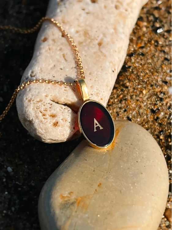 Gold-plated amber pendant with engraved A initial, close-up detail