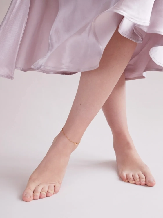 Gold-plated ankle bracelet worn on the leg in a summer style