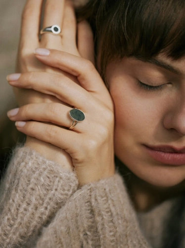 Oval nephrite from Lower Silesia set in a sterling silver ring worn on the hand in a winter-inspired scene.