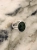 Silver ring with an oval green nephrite stone photographed on a light marble surface.